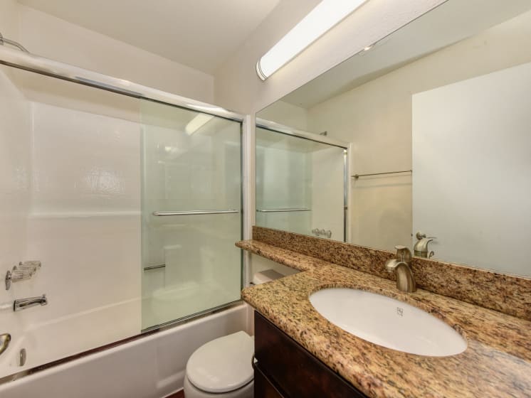 Bathroom with Granite Quartz Countertops, Vanity Mirror,  Glass Shower Enclosure and Bathtub